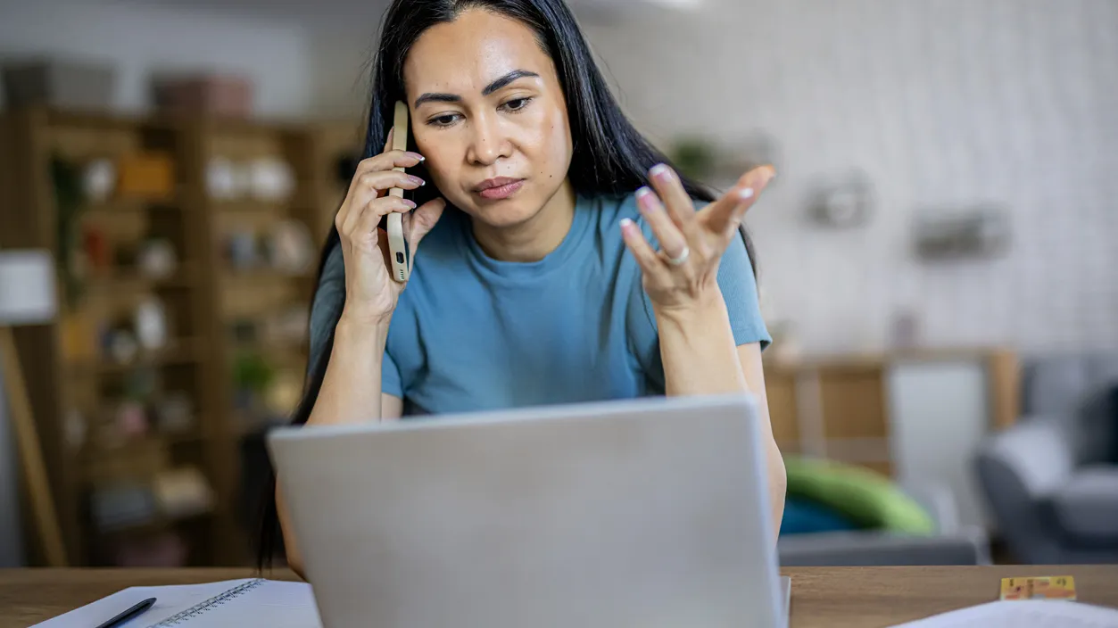 Remote employee looking worried while talking on a mobile phone during work from home, illustrating business challenges, problem solving, and professional communication.