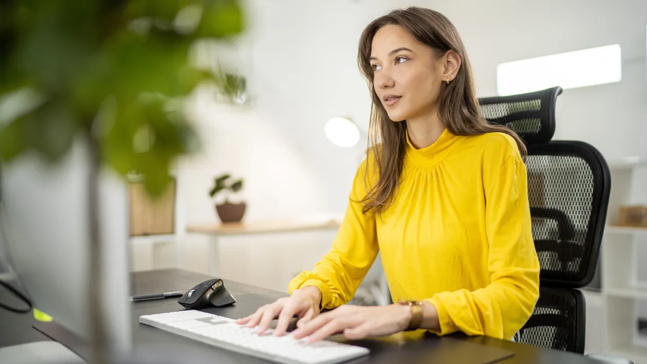 Young woman sitting at desk and working on compter in office